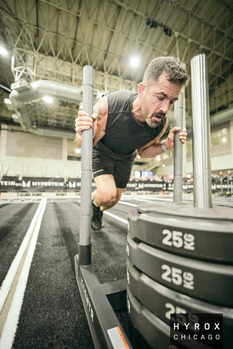 Todd Hollander pushing a weighted sled during a HYROX competition